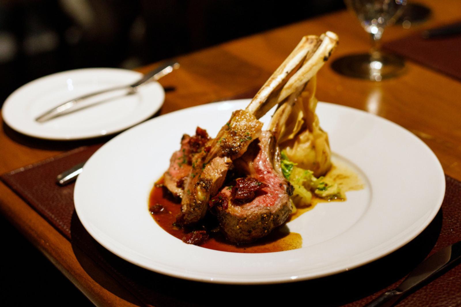 two pan seared lamb chops on a white plate with vegatables